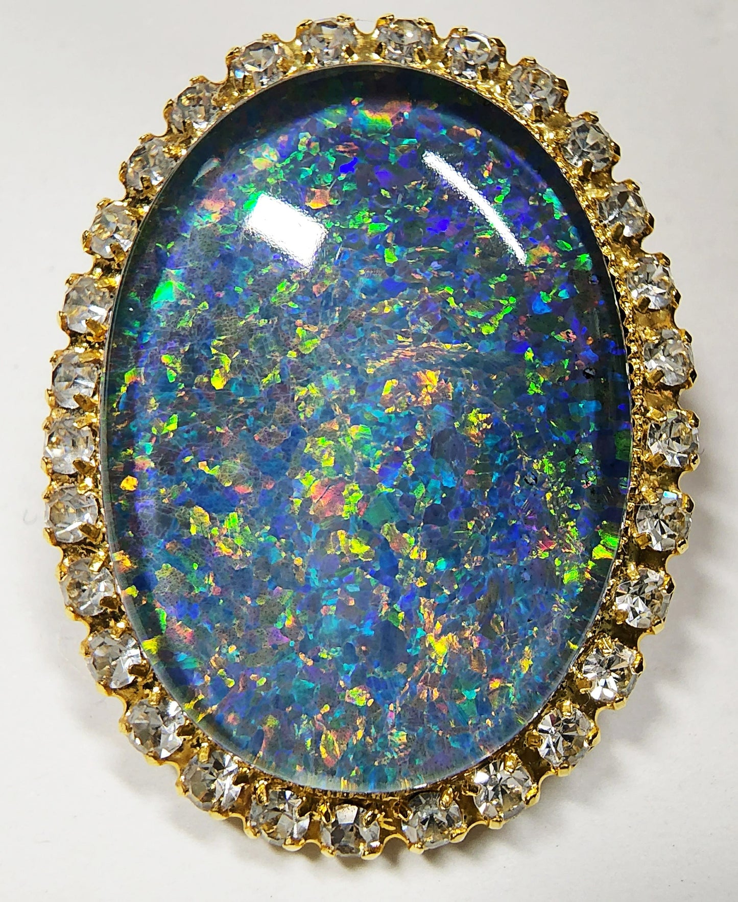 53662.0 - Gullfarget brosje sett med Swarovski-rhinestones som omgir en stor høykvalitets 25 x 18 mm ovalskåret australsk opaltriplett