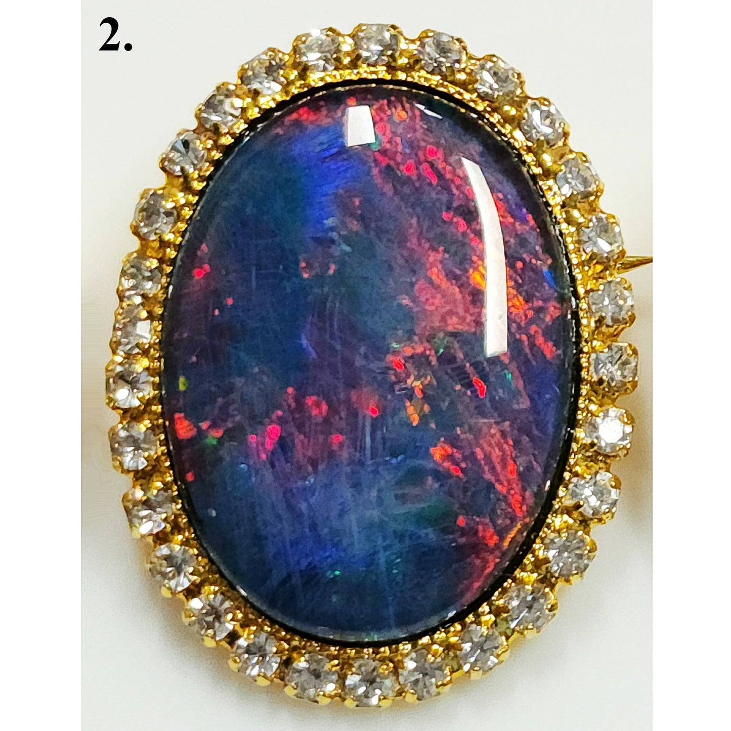 53662.0 - Gullfarget brosje sett med Swarovski-rhinestones som omgir en stor høykvalitets 25 x 18 mm ovalskåret australsk opaltriplett
