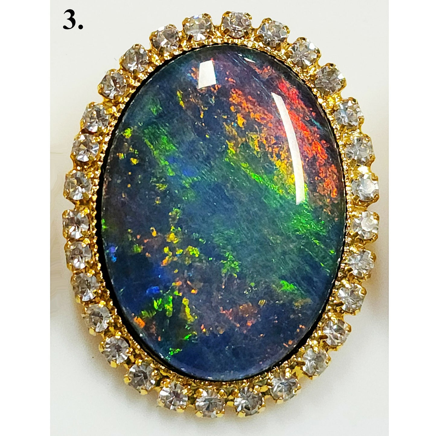 53662.0 - Gullfarget brosje sett med Swarovski-rhinestones som omgir en stor høykvalitets 25 x 18 mm ovalskåret australsk opaltriplett