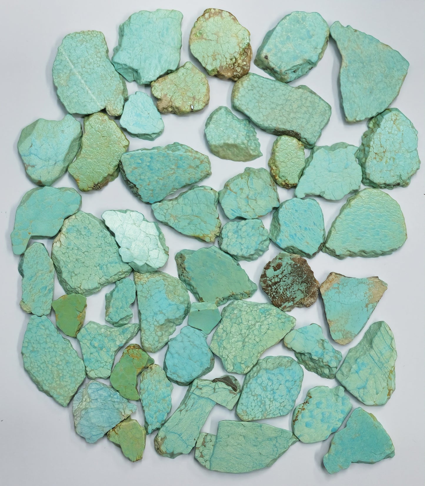Collection of turquoise stone chips on a white background