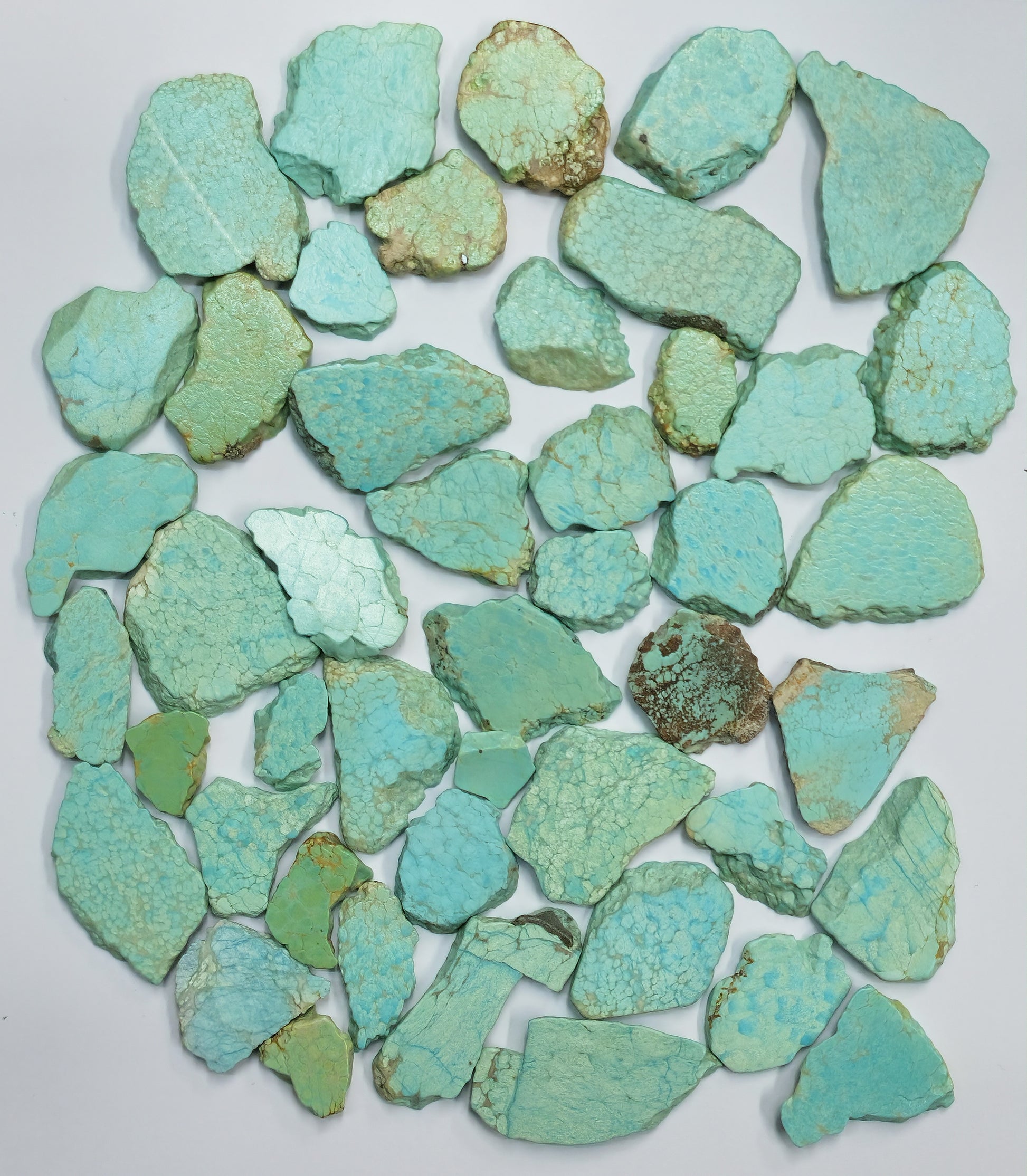 Collection of turquoise stone chips on a white background