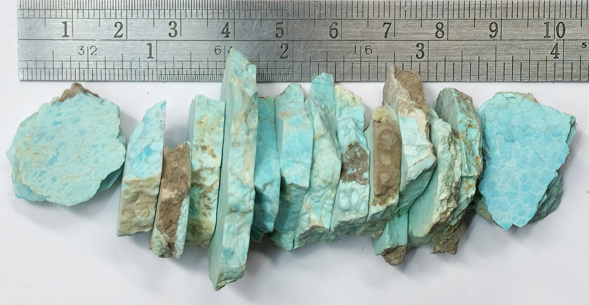Turquoise mineral specimens with a ruler for scale on a white background
