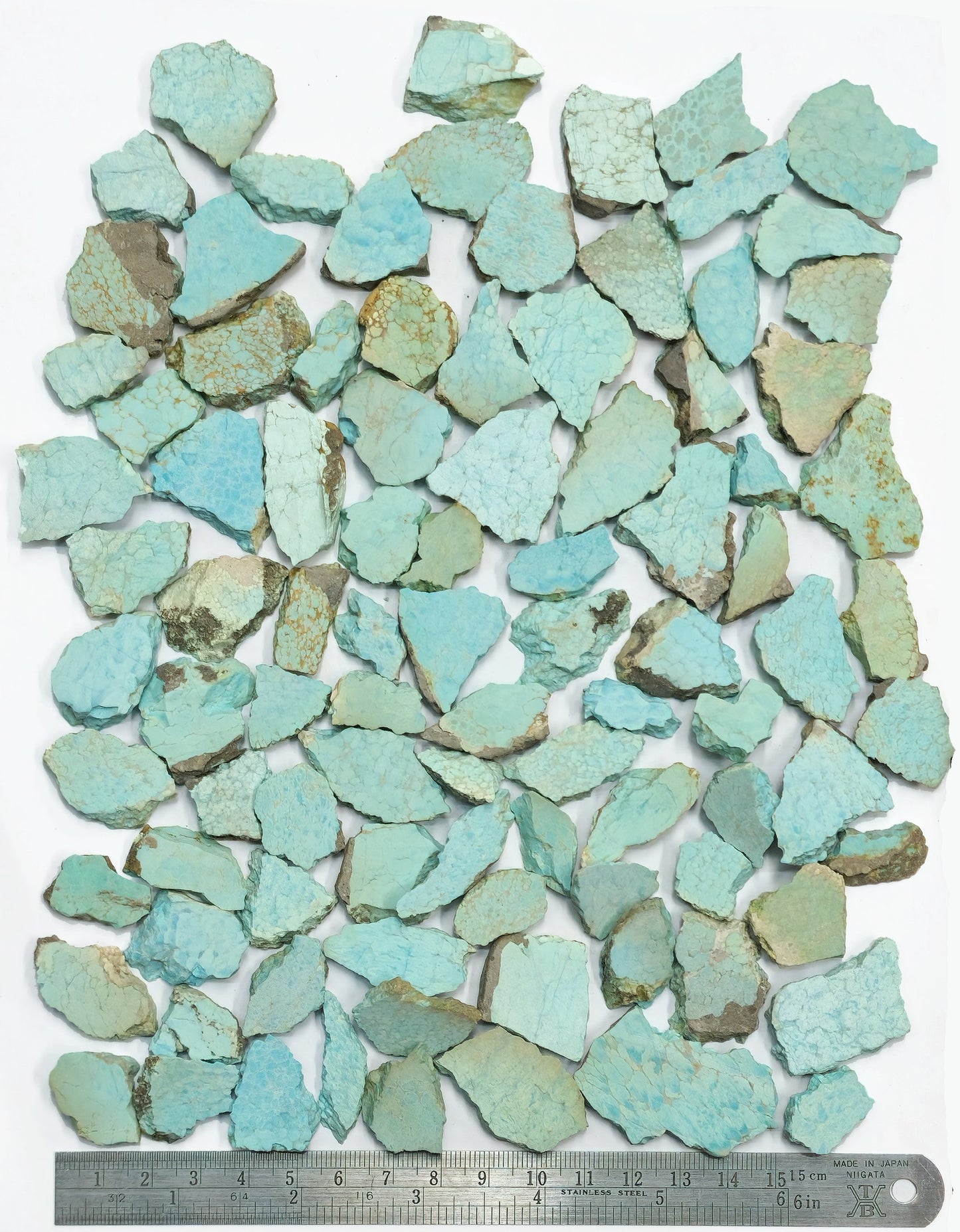 Collection of turquoise ceramic tiles with a ruler for scale on a white background