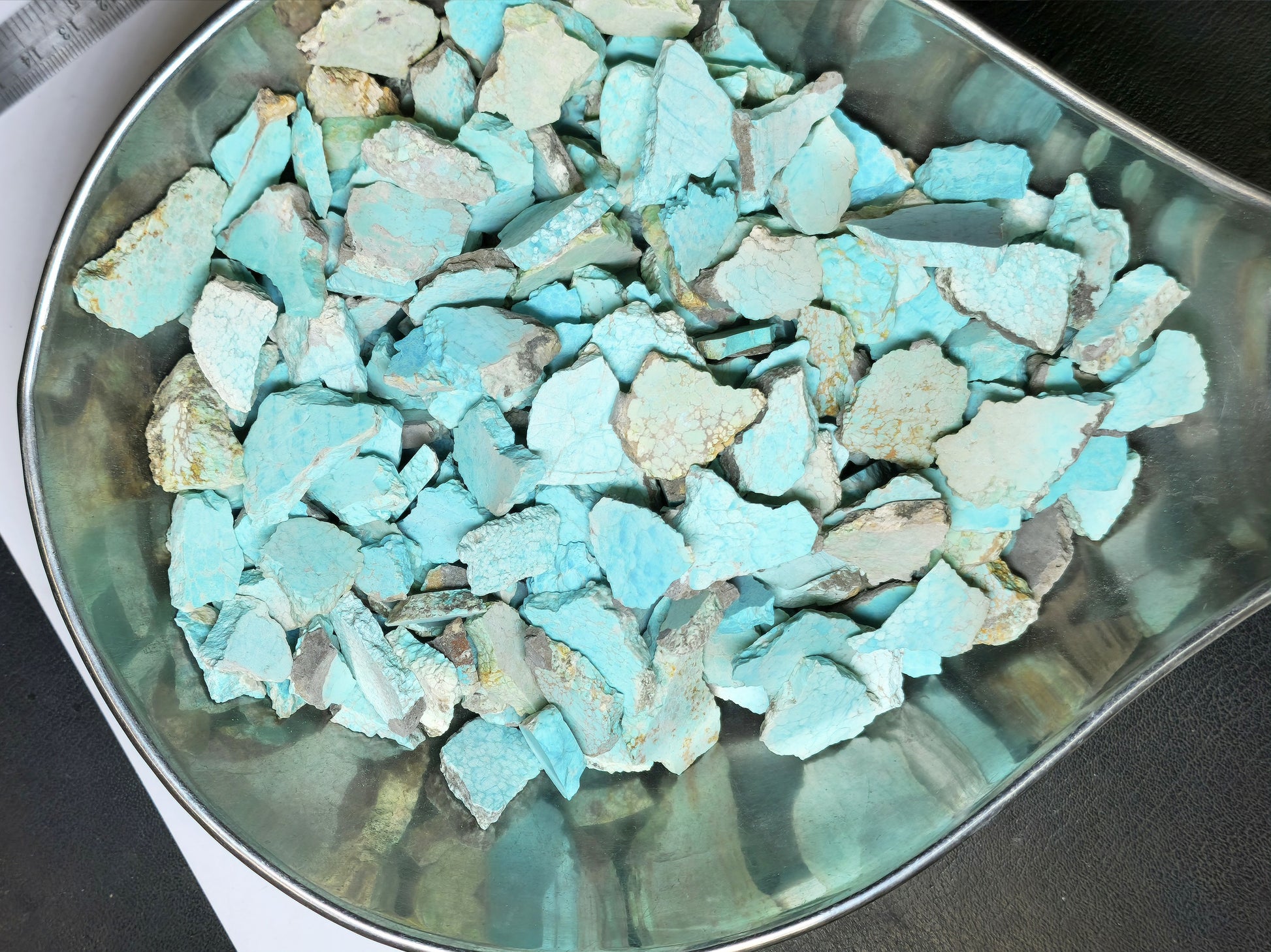 Turquoise stone chips in a metallic bowl